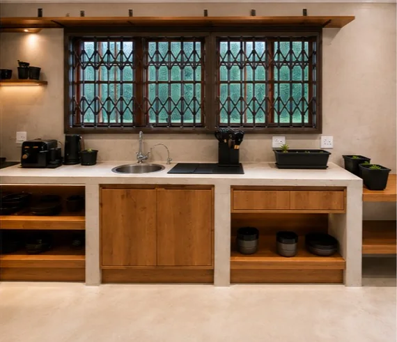 Cement counter with oak drawers and open shelves under a burglar-barred window